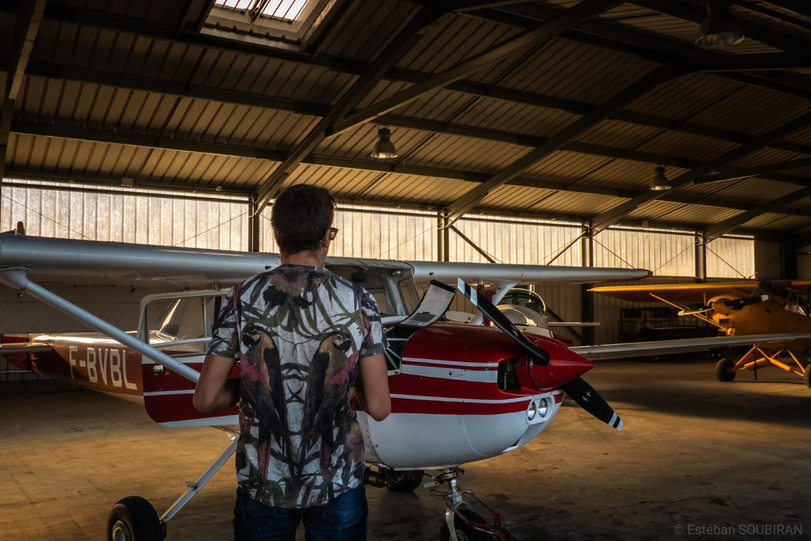 Photo d'Estéban de dos face à un avion rouge